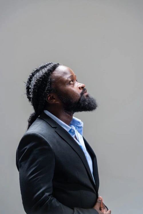 Serge Kakudji de profil, vêtu d’une veste sombre