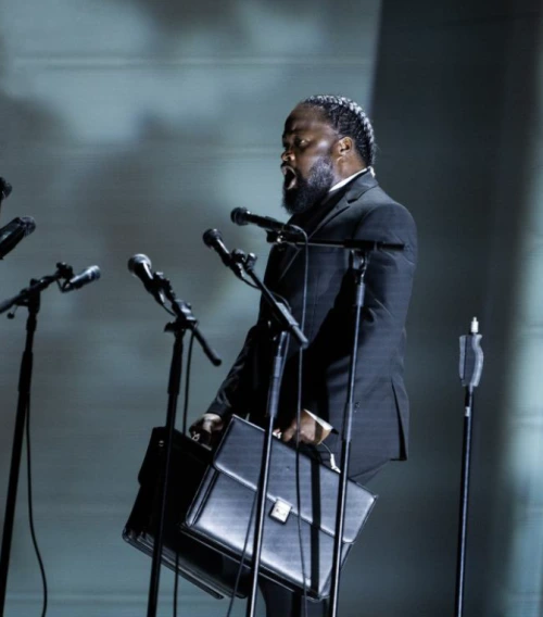 Serge Kakudji chantant sur scène devant plusieurs microphones