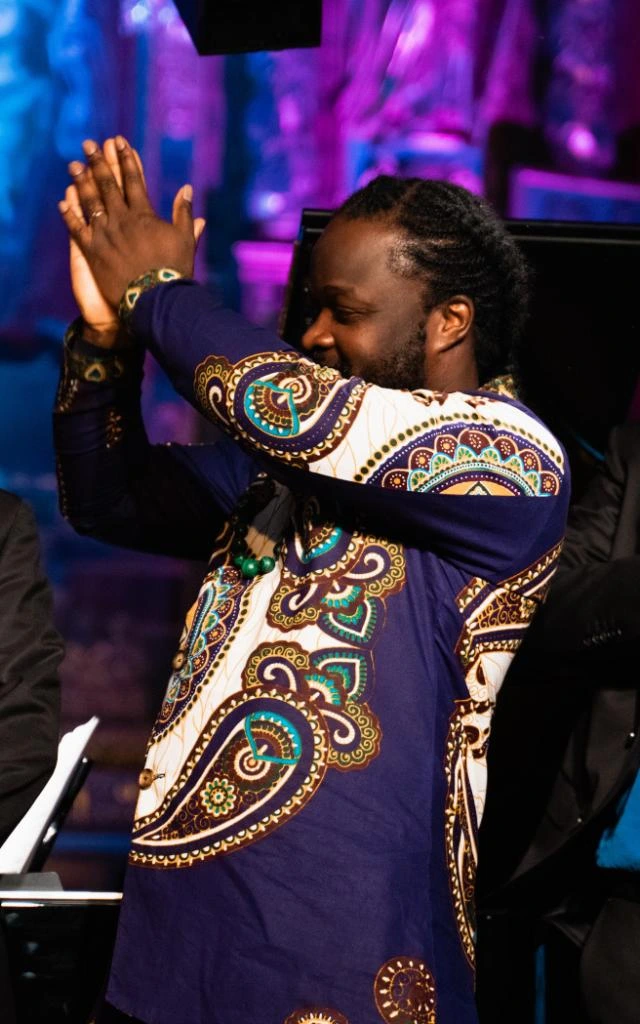 Serge Kakudji applaudissant devant un public lors d’un concert