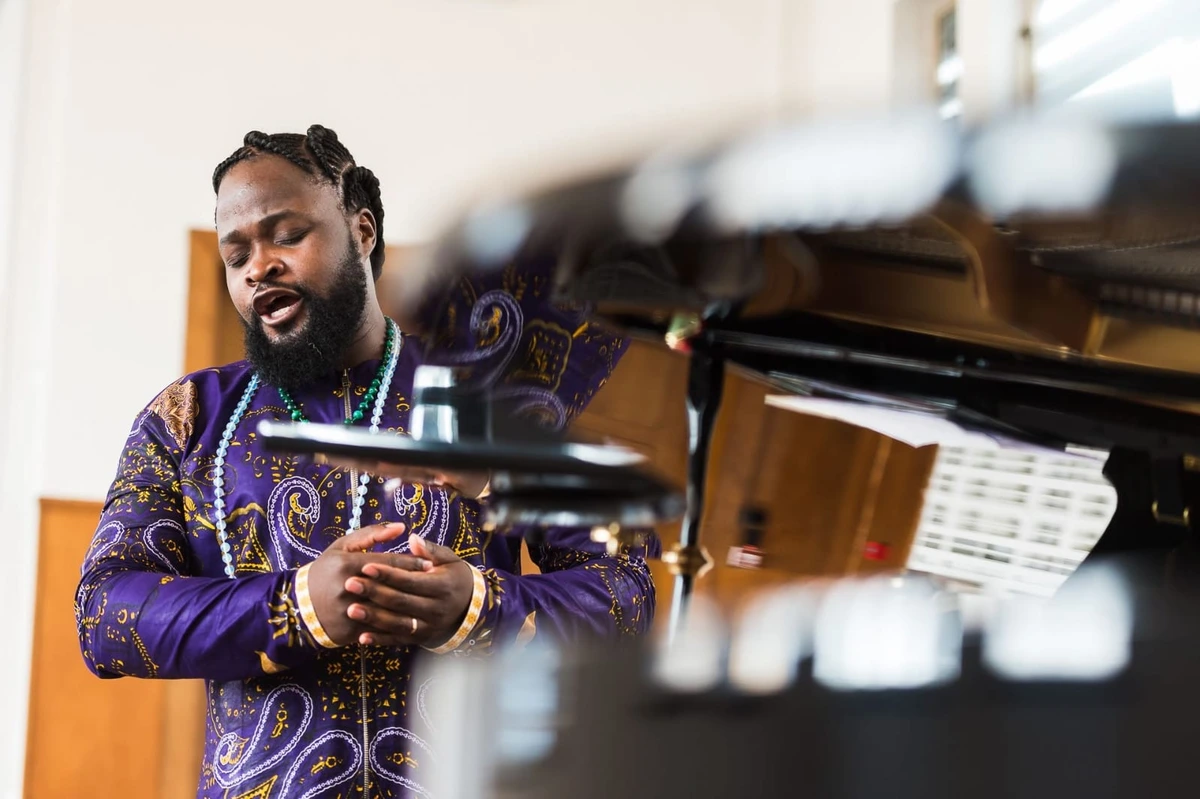 Serge Kakudji chantant à côté d’un piano